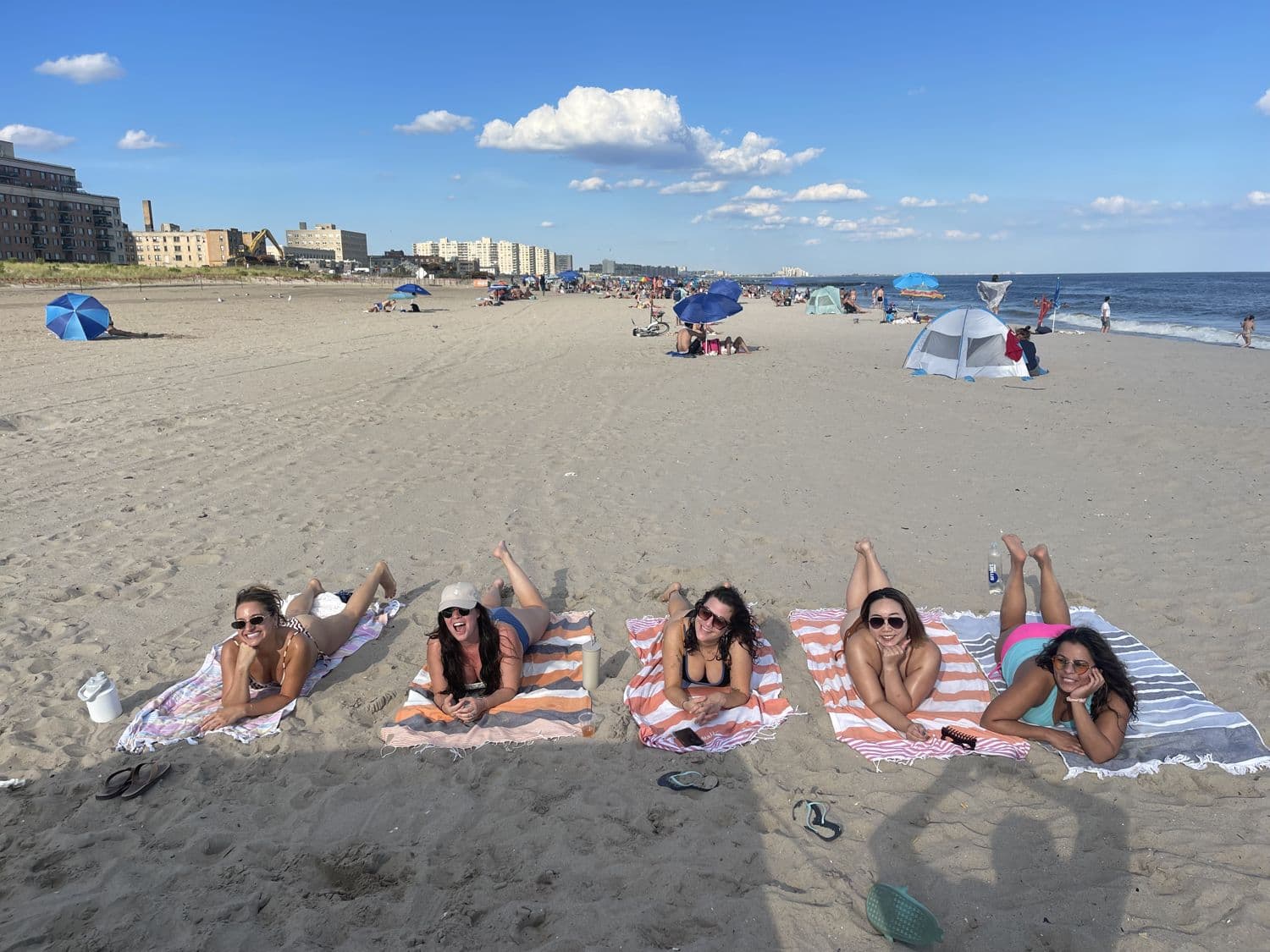 Friends lined up on beach towels on white sand