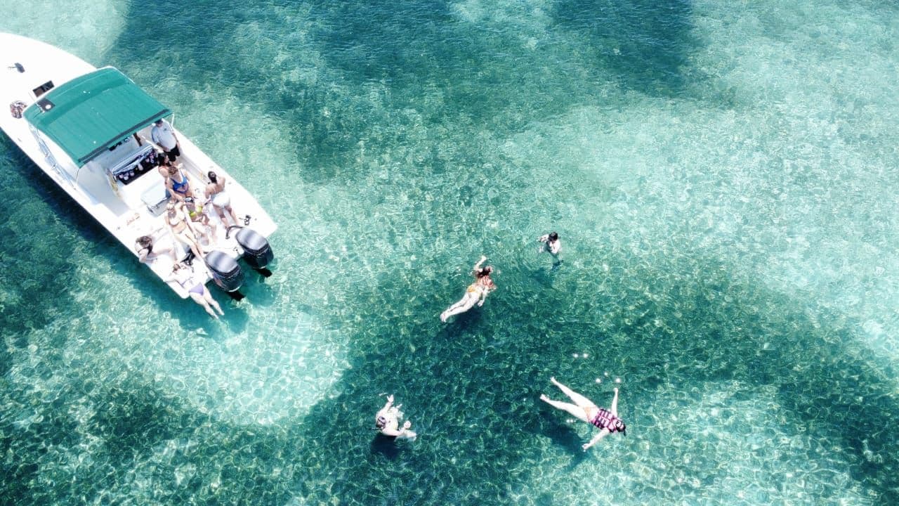 Anchored over clear water, swimmers off the bow