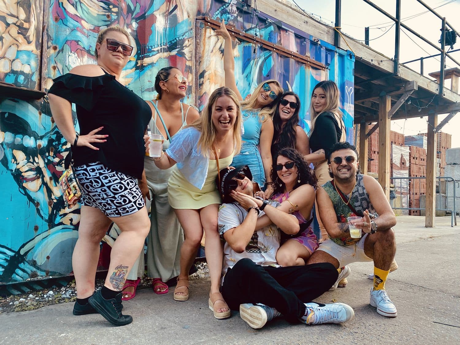 The crew posing in front of a mural in Brooklyn