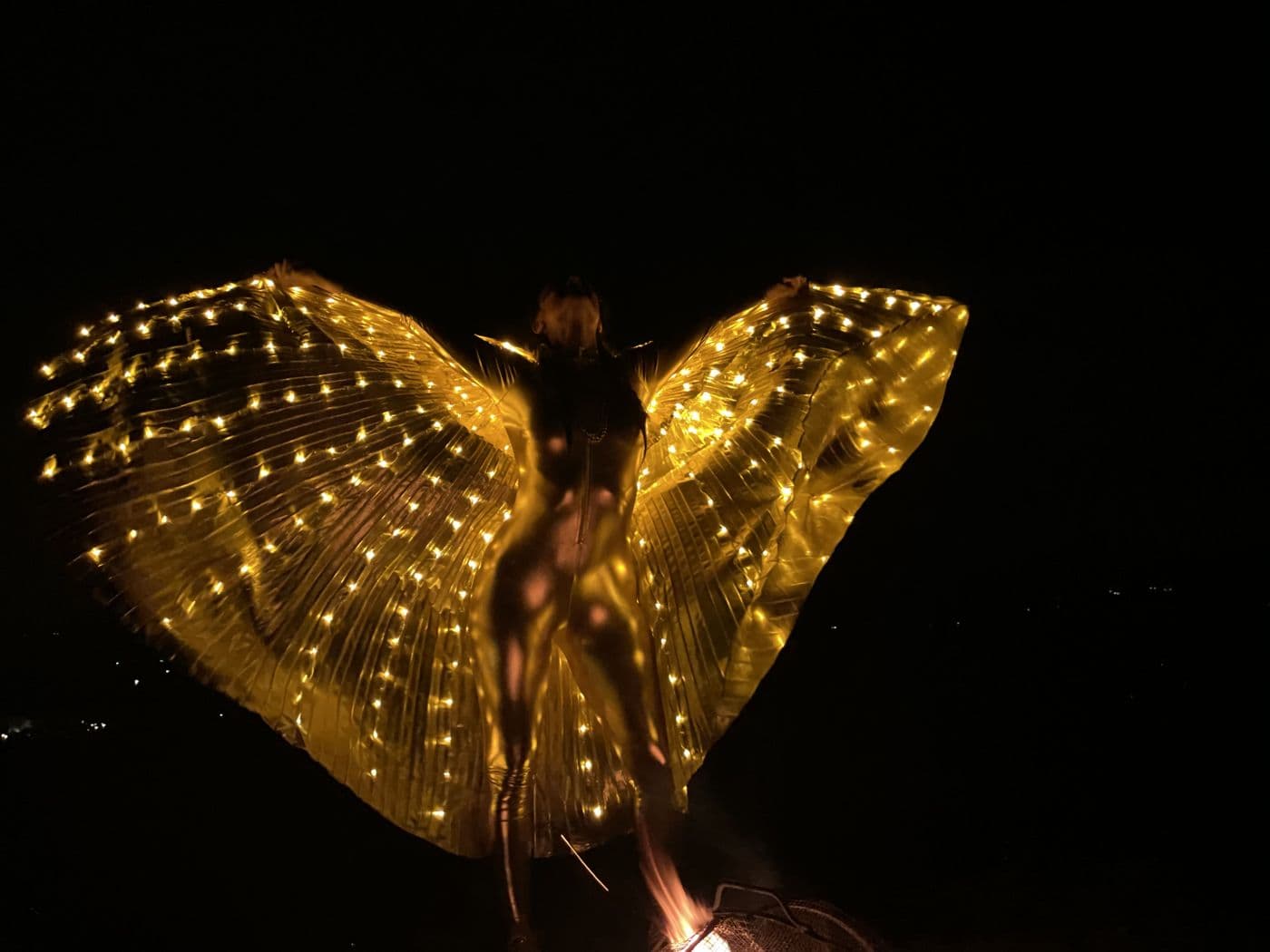 Performer with illuminated wings at night